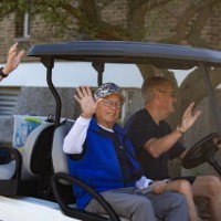 3 GVSU Alumni wave on golf cart as they pass by